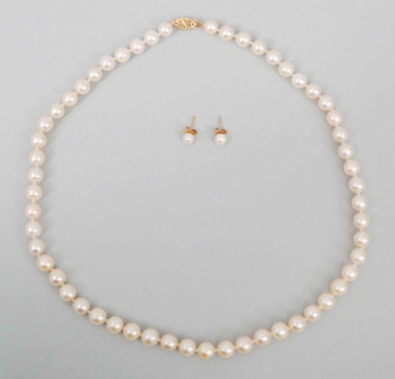 14K Gold & Pearl Necklace & Earrings: Comprising a necklace with pearls ranging from 7.0 mm to 7.5 mm with slight rose overtone and bluish orient. Together with a pair of pearl stud earrings. Necklace 17 1/2". A copy of the insurance appr