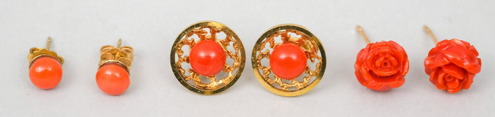 3 Pairs of 14K Gold & Coral Earrings: Comprising a pair of coral studs, a a carved floral pair, and a deco style pair. 4.3 dwt total weight.