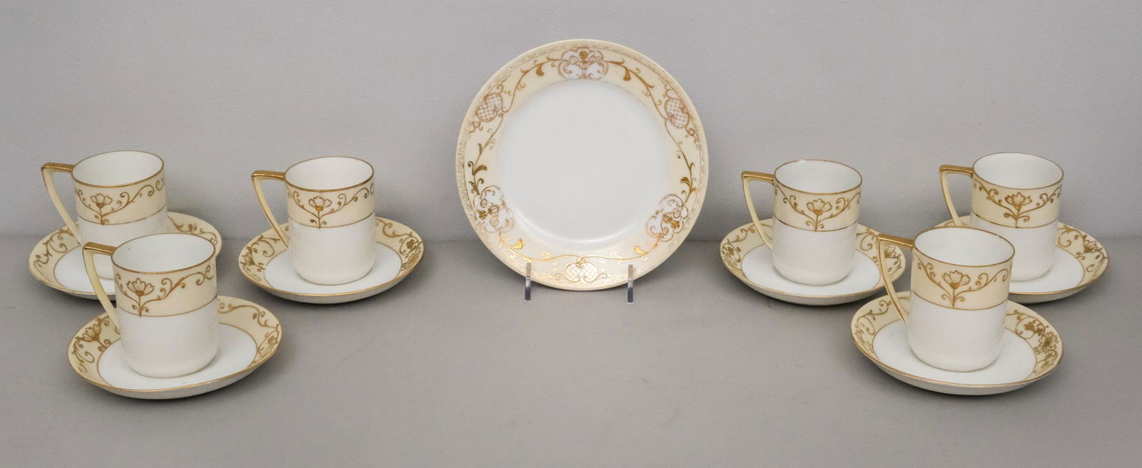 Group of Noritake Antique Gold Encrusted Porcelain: Comprising 6 cups and saucers (one with chip) and a bread plate. cup 2 1/4" x 2 3/4".