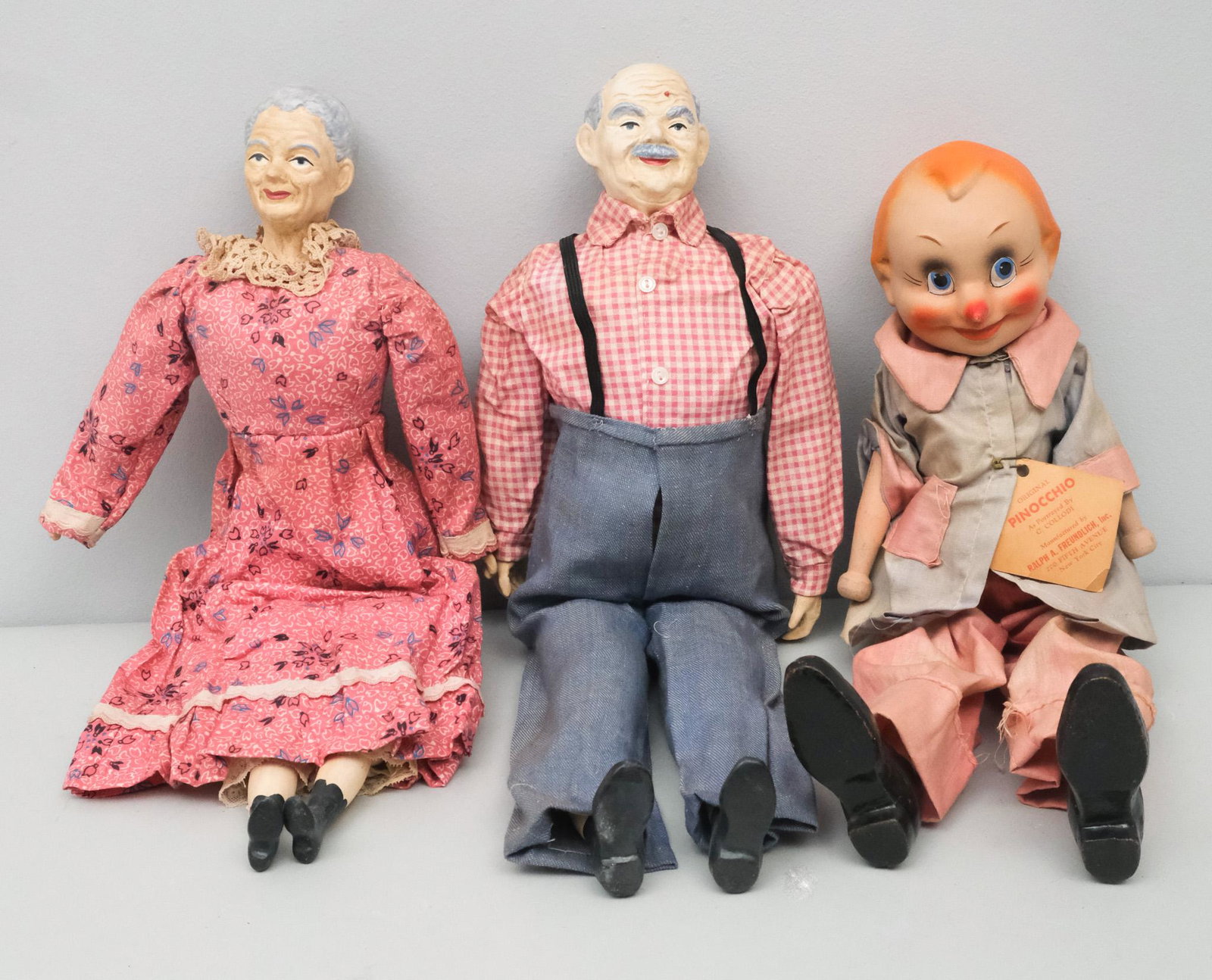 Group of Character Dolls: Group includes a Ralph A. Freundlich Pinocchio doll (circa 1930/40) with articulated legs and original tag; a grandmother and a grandfather doll with handmade clothes and hand painted heads.