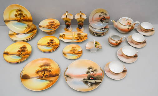 Noritake Porcelain Hand Painted Landscape Service: Antique partial service comprising: (2) cake plates, a divided relish, (4) salad plates, (2) dessert plates, (2) basket handled vases, a small compote, a lemon dish, (2) larger side plates, (6) bread