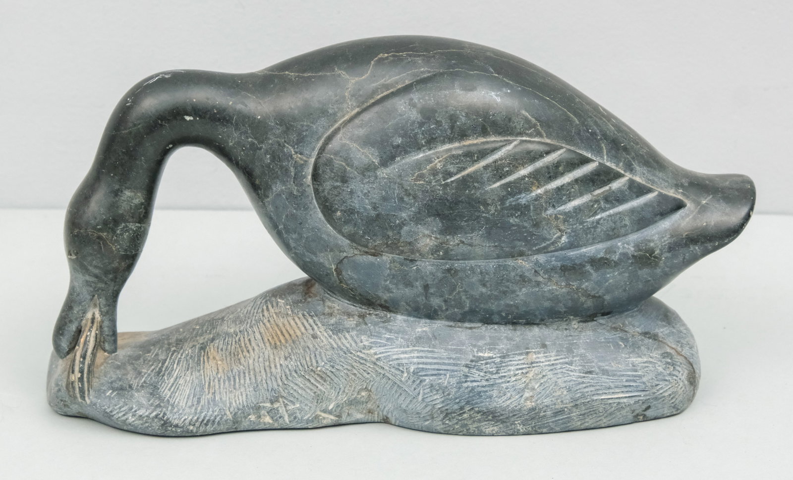 Carved Stone Sculpture of a Goose: Depicting a goose biting at a reed. Illegibly signed. 12 1/2".