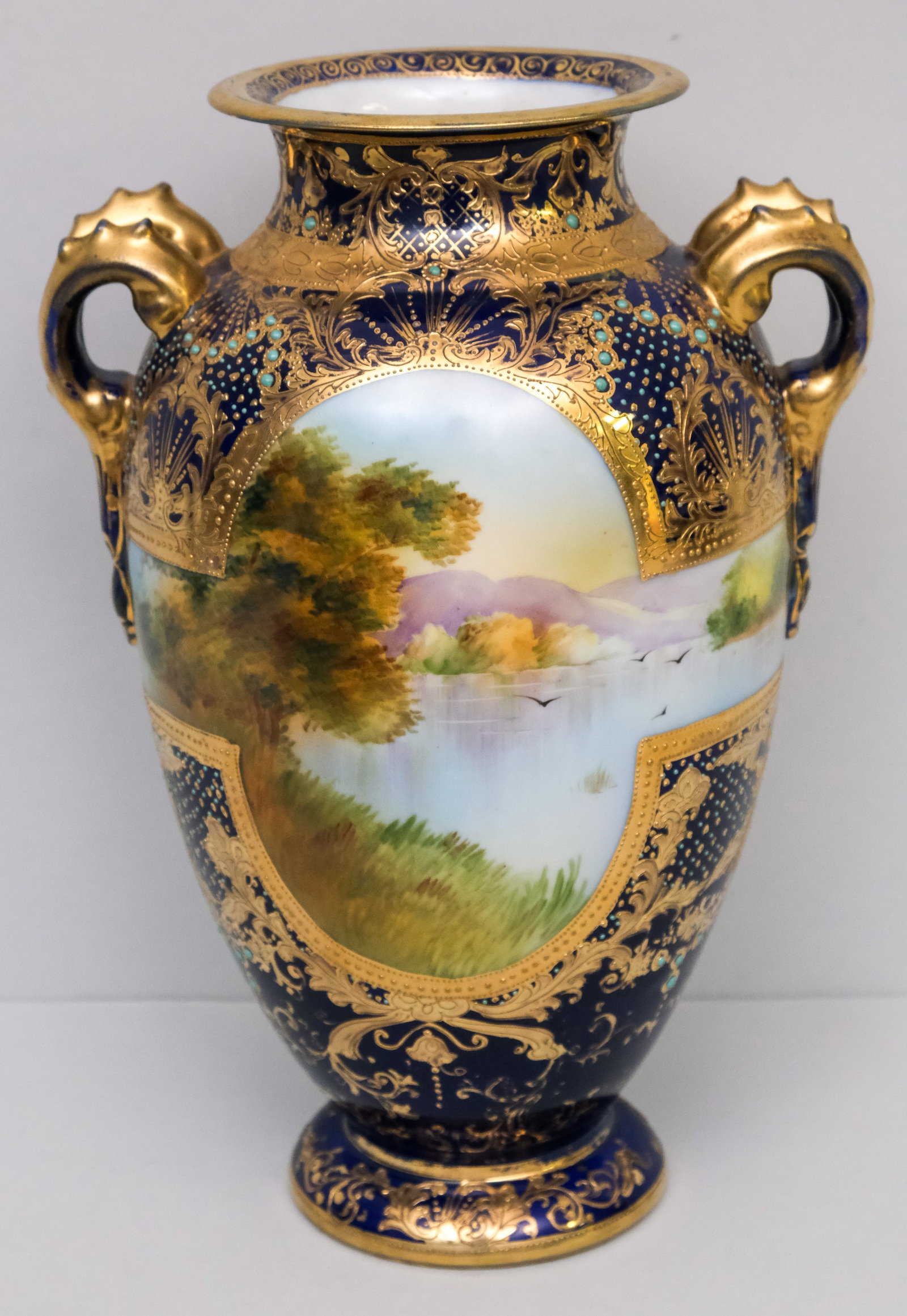 Large Antique Morimura Gumi Porcelain Nippon Vase: With Moriage jewels and gilded cobalt field, landscape surround and organic handles. 12 1/4".