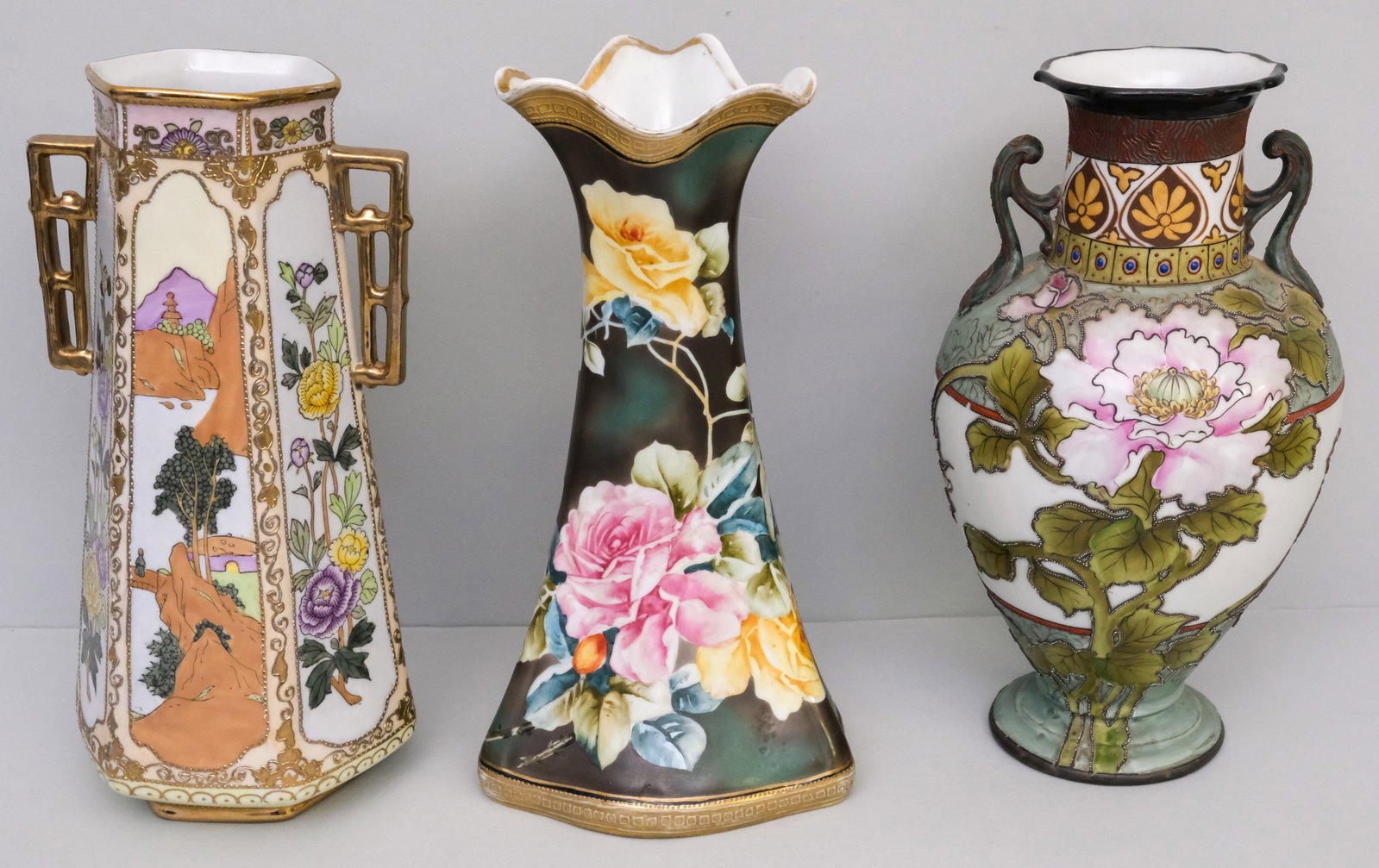 Three Antique Nippon Porcelain Vases: Comprising a Morimura Gumi ruffled rim vase, an unmarked Moriage example with mountain scenes, and an Imperial Nippon Moriage vase with heavily outlined flowers (some Moriage missing). 12".