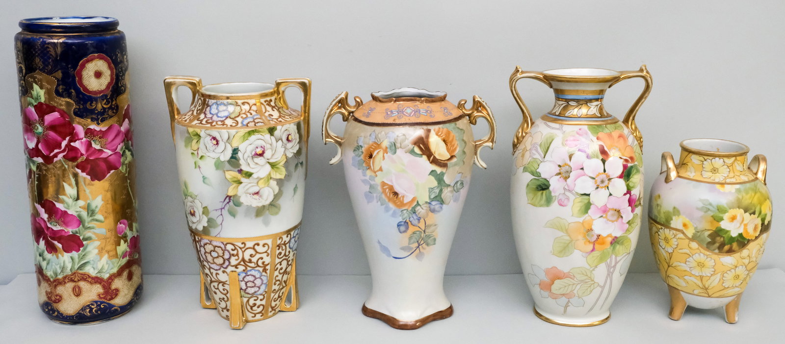Five Antique Nippon Porcelain Vases: Comprising a large unmarked cobalt and gold vase, a Morimura Gumi vase with angular pierced feet and handles, an unmarked vase with tan flowers, a Morimura vase with fine floral detailing, and a Morim