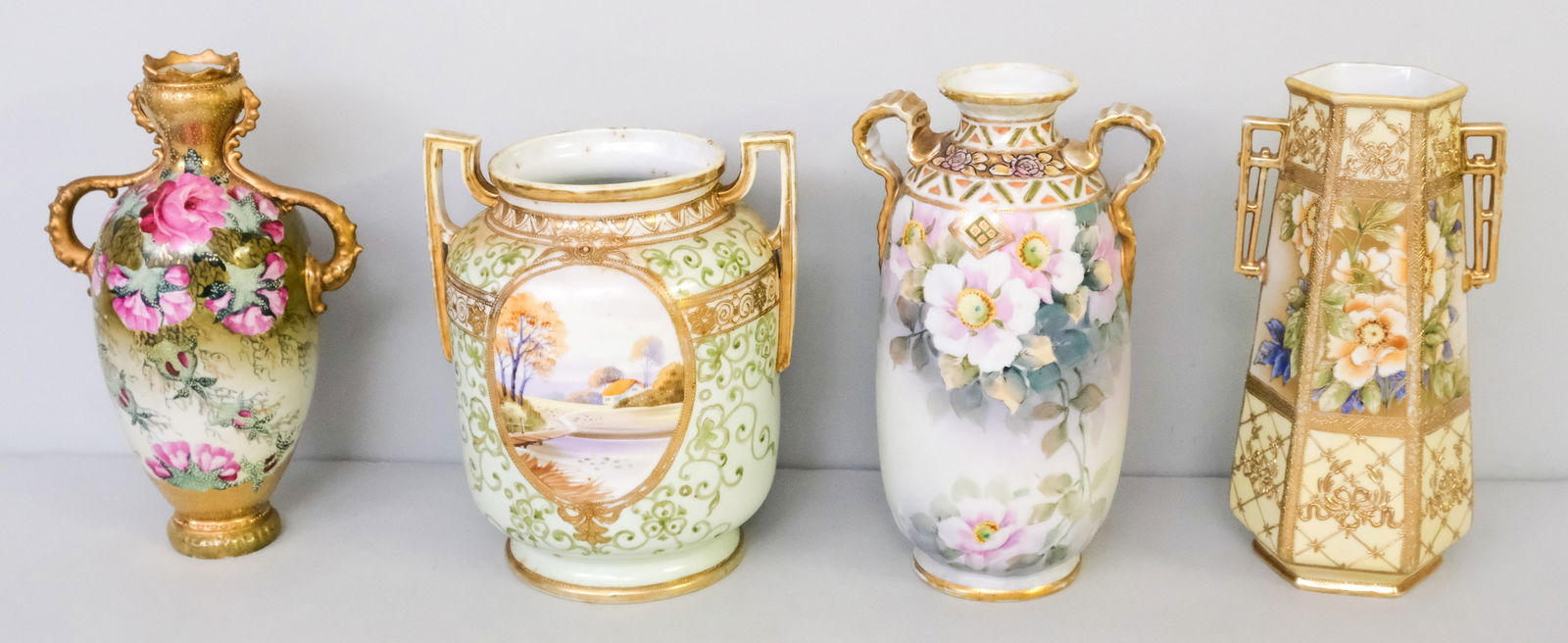 Four Antique Nippon Porcelain Vases: Comprising a Noritake hexagonal vase with heavy Moriage, a wide bodied Morimura Gumi vase, an unmarked slender necked vase (restored rim), and a Morimura vase with ribbon handles. 8 7/8" to 10".