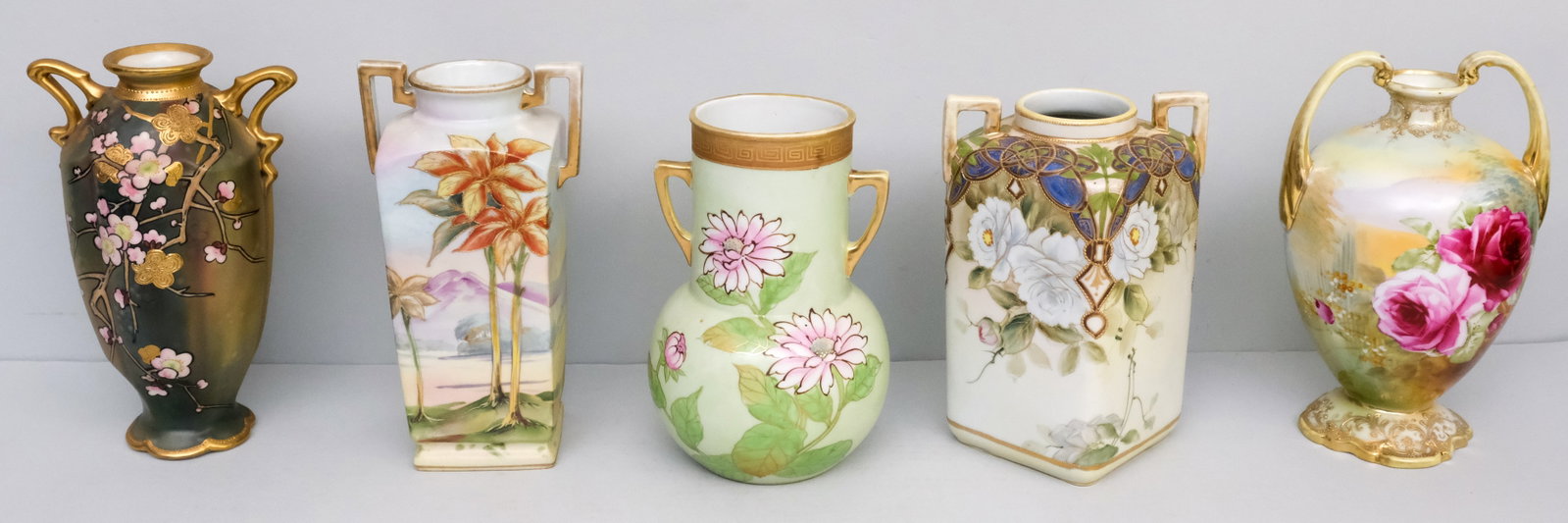 Five Antique Nippon Porcelain Vases: Comprising a Morimura vase with organic handles and Moriage gilded cherry blossoms, a Morimura Gumi with oversized handles and roses, a Nippon vase with light green field, a square bodied Imperial Nip
