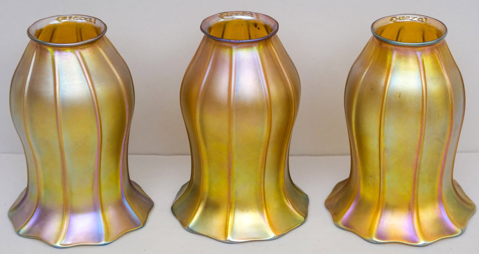 Three Antique Quezal Art Glass Lampshades: Iridescent glass bodies with pulled green feather decor. 2 1/8" x 5" x 3 1/4".