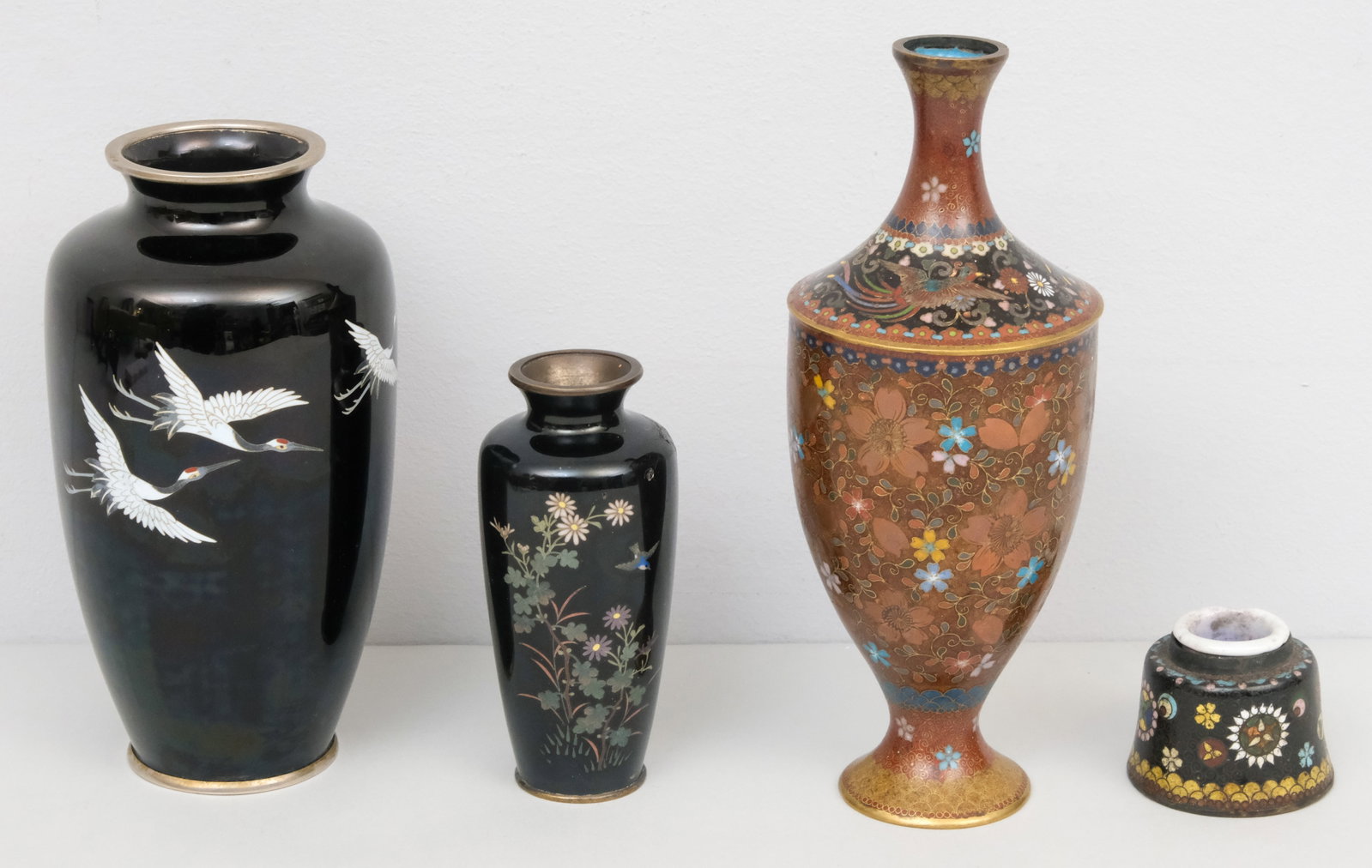 Group of Fine Antique Cloisonne: Comprising three vases, including a black field with cranes by Sato, a goldstone vase, and another with birds and bamboo (damage to shoulder) an ink pot (chip to insert). Tallest 8 1/2".