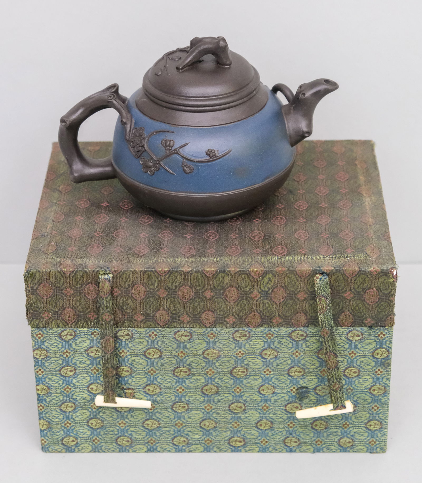 Yixing Clay Teapot: Figural branching plum applique with blue painted band. Marked on bottom. In fitted case. Teapot 4" x 6 3/4