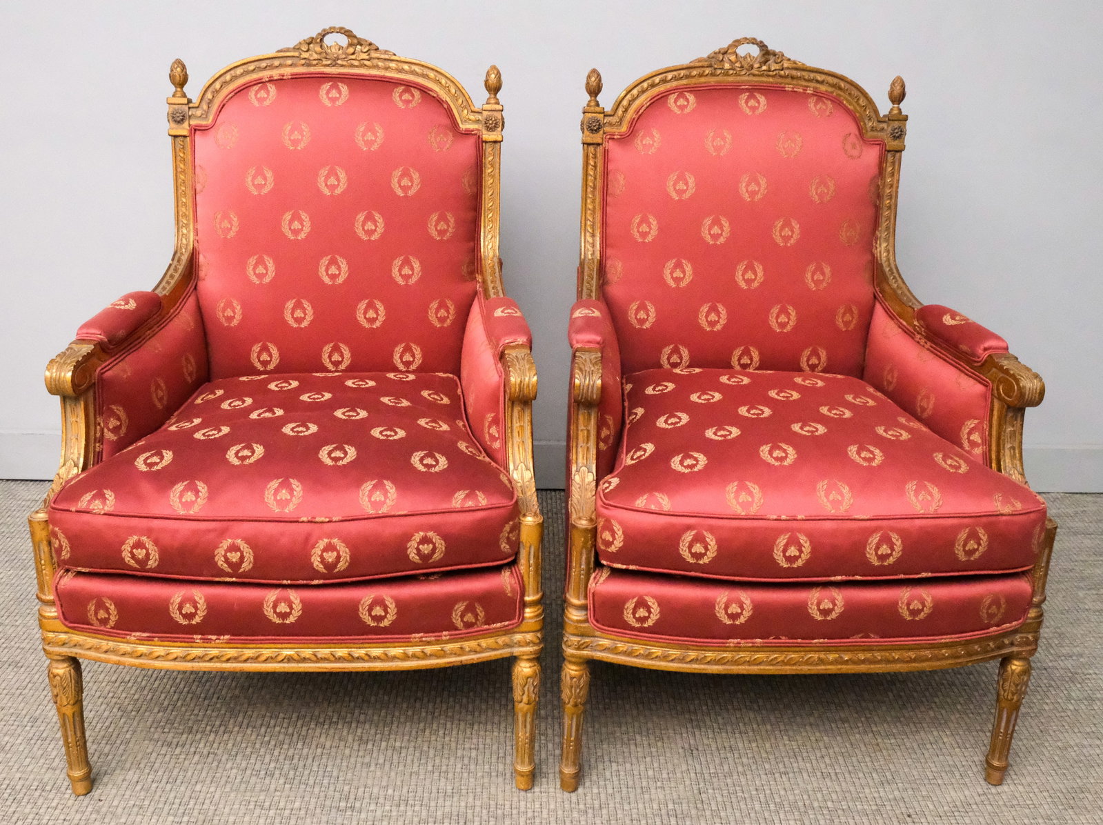 Pair of Louis XVI Bergere Chairs: Pair of French Louis XVI Bergere chairs with red bee and wreath pattern upholstery, carved gilt frame, 39" H x 25" W x 24" L.