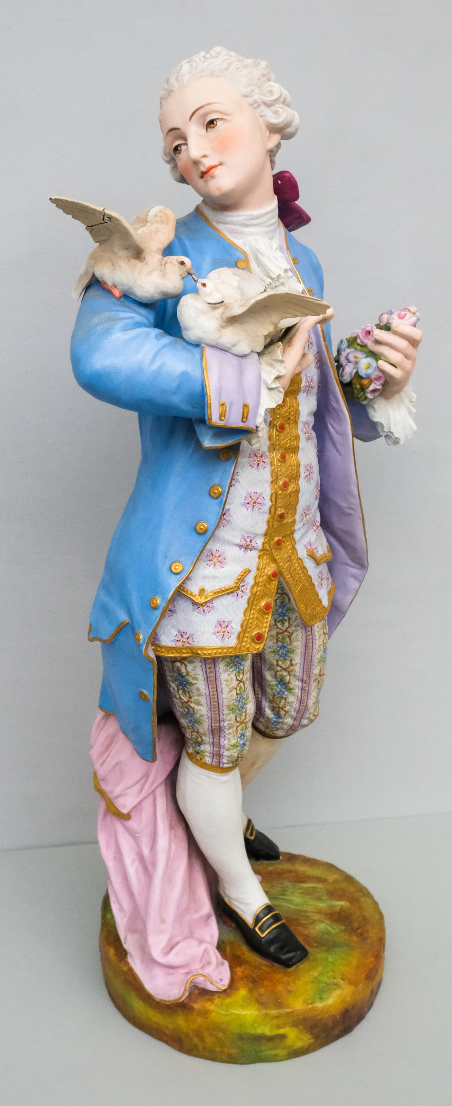 Large Chelsea Bisque Figure of a Man: Depicting a gentleman holding a pair of doves and a wreath of flowers. 26". Marked as shown.