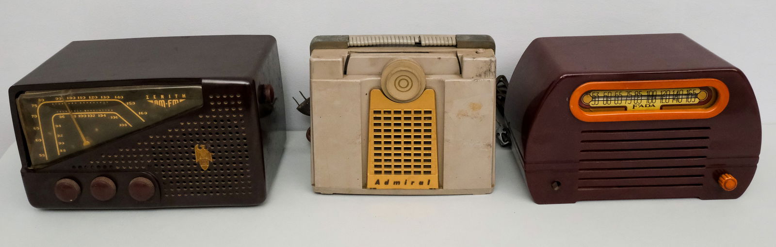 Group of 3 Vintage Bakelite & Plastic Radios: Comprising a Fada Catalin "Temple" Model 652 (missing one knob), a Zenith 7E02, and an Admiral radio in grey.