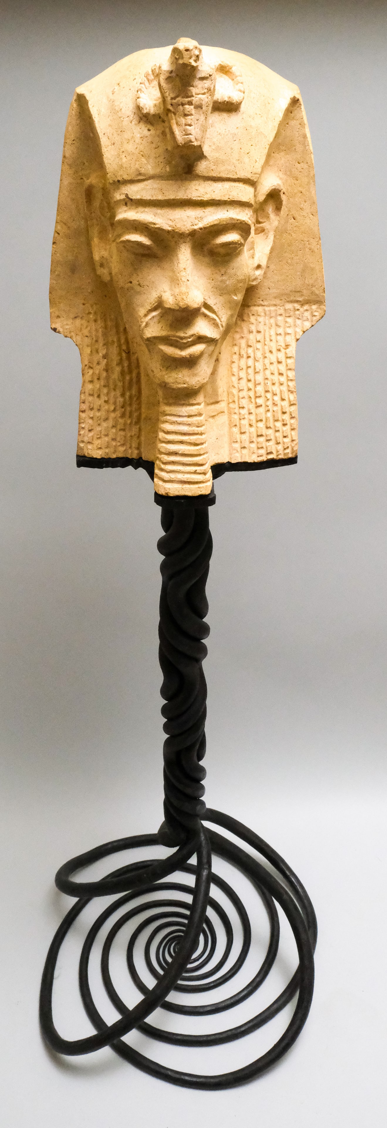 Carved Stone Bust of King Akhenaten: Vintage carved stone bust of the heretic King Akhenaten on a molded top, twisted, wrought iron stand, 51" H x 18" diameter.