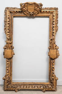 Early English Giltwood Trophy Frame 27 1/2" x 50": English, 18th century, impressively carved and gilded with heraldic ornament. Overall 40" x 64 1/2", rabbet 27 1/2" x 50", 6 1/2" molding