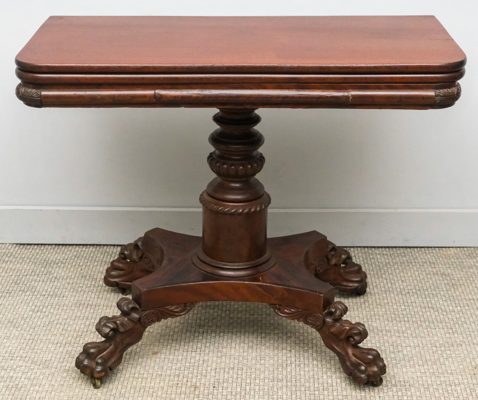 Classical Carved Mahogany Claw-Foot Game Table: American, early 19th century, having carved column and feet on casters, 18" (closed) 36" (open) x 36" x 29 1/2" H.