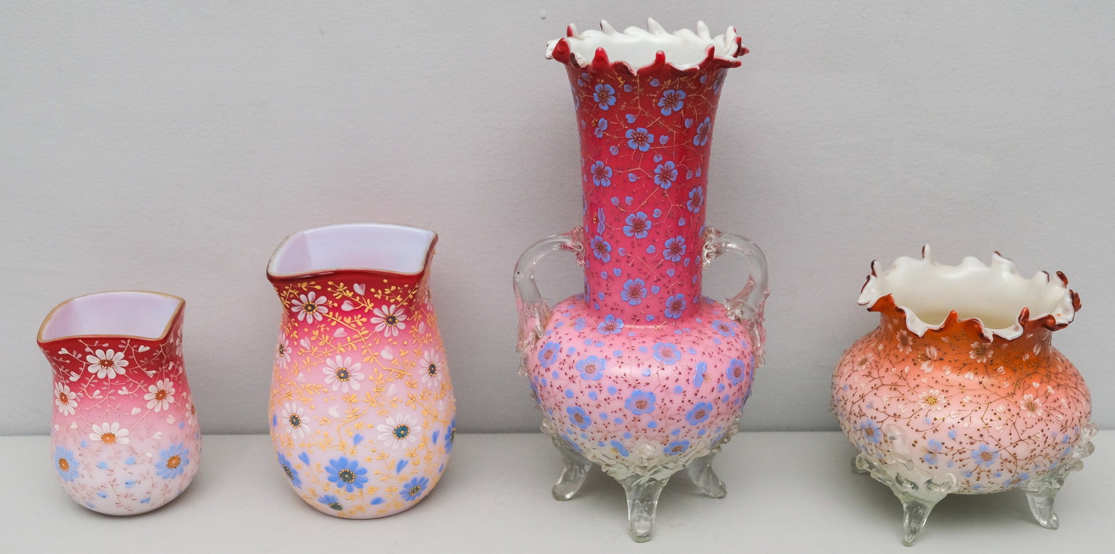 Four Antique Webb or Harrach Type Glass Vases: Cased glass with white to ruby glass with thick enameling. Varied forms, including a four-footed example with shouldered handles.