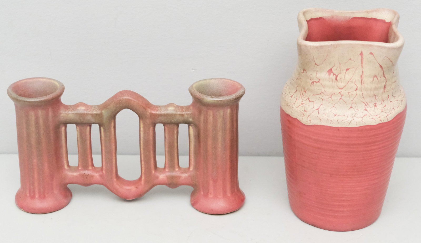 Two Pieces of Muncie Art Pottery: Comprising a gate-form double bud vase in air blue over rose, and a ribbed body vase with blown open white mouth. Marked as shown. Measuring 7 1/2" and 8 3/4" respectively.