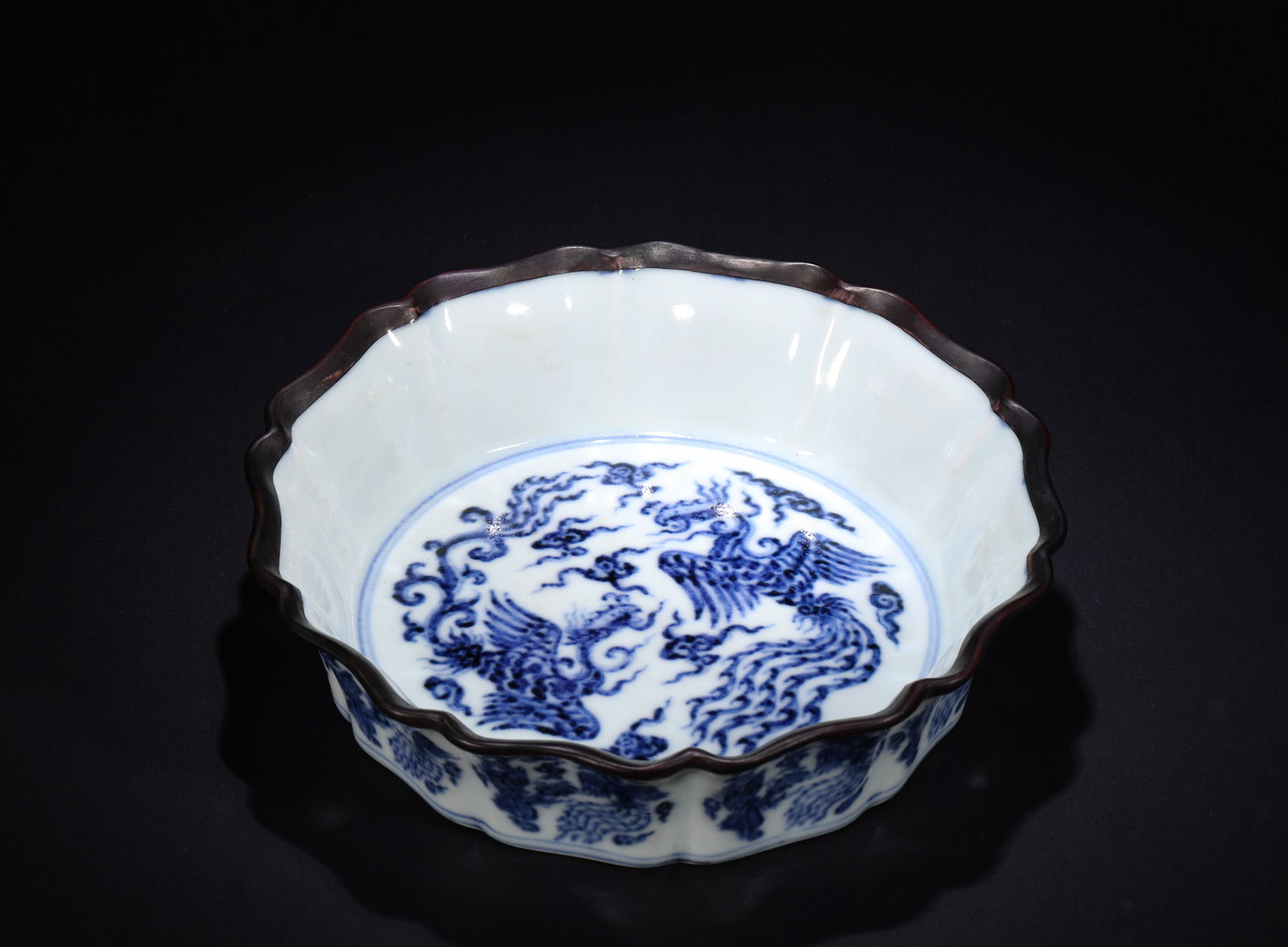 IN THE MING DYNASTY, BLUE AND WHITE PHOENIX-PATTERNED FLOWER-MOUTH WASHBASIN: Name IN THE MING DYNASTY, BLUE AND WHITE PHOENIX-PATTERNED FLOWER-MOUTH WASHBASIN Dimensions H:7.5cm W:17.3cm This is a blue and white porcelain washbasin with phoenix patterns and a sunflower mouth i