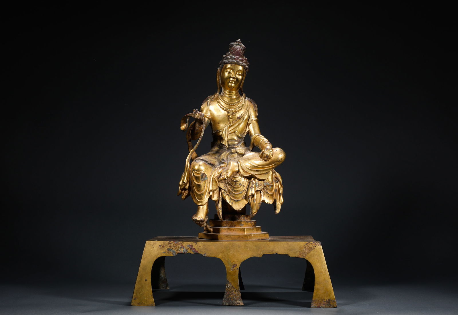 TANG DYNASTY, GILDED BRONZE BENCH GUANYIN: Name TANG DYNASTY, GILDED BRONZE BENCH GUANYIN Dimensions H: 44 CM; W: 32 CM; WEI GHT: 6470 GTHIS IS A GILDED BRONZE SITTIN G STATUE OF THE FREE AND EASY GUANYIN IN THE STYLE OF THE TAN G DYNASTY, WHI