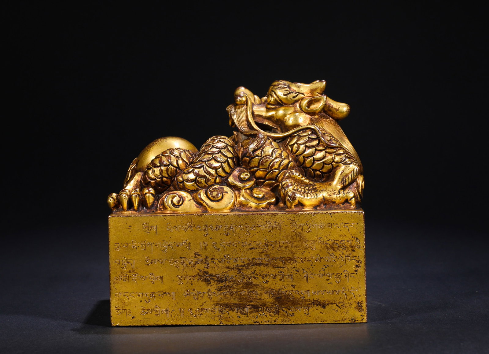 A GILDED BRONZE SEAL WITH A COILED DRAGON KNOB MADE BY THE IMPERIAL WORKSHOP OF THE QING DYNASTY: Name A GILDED BRONZE SEAL WITH A COILED DRAGON KNOB MADE BY THE IMPERIAL WORKSHOP OF THE QING DYNASTY Dimensions H:14cmW:13.8cmWeight:2240g This artifact is a gilt-bronze seal with a coiled dragon kno
