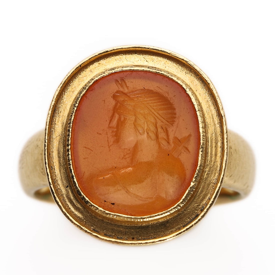AN INTAGLIO RING WITH A CARNELIAN PORTRAIT IN 22K GOLD SETTING: Dimensions: Inner diameter: 16.7 mm; Weight: 7.4 g Description: This elegant ring features a finely carved intaglio portrait of a classical figure facing left, set in a smooth oval bezel. The intaglio