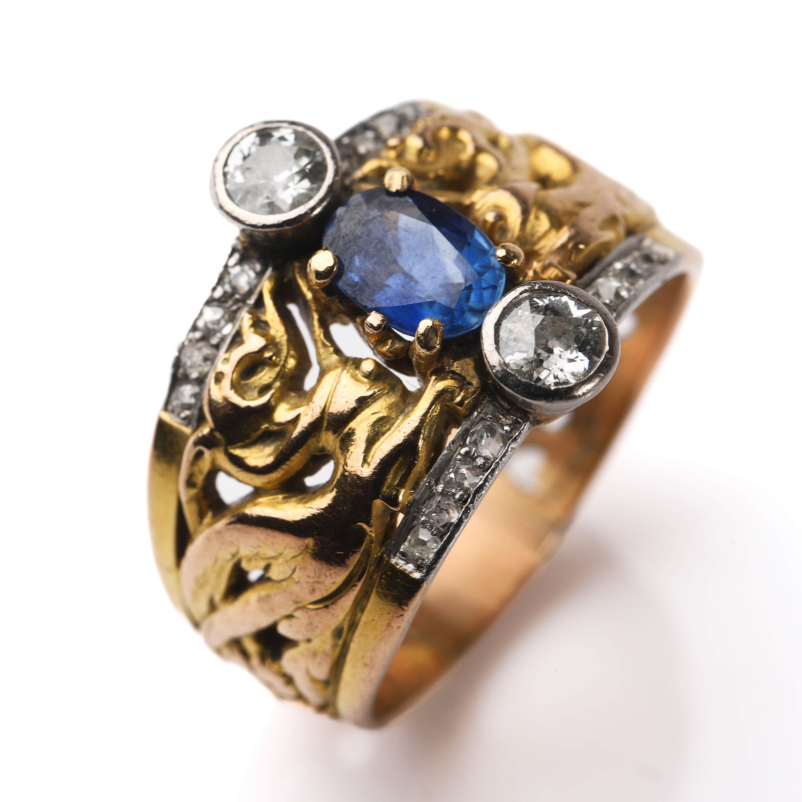 AN ANTIQUE SAPPHIRE AND DIAMOND RING, GOLD MOUNT: Dimensions Inner diameter 0.78 in (19.9 mm); Width 11/16 in (17 mm); Weight 10.5 g Description An antique gold ring featuring an oval-cut sapphire of rich blue color, flanked by two old-cut diamonds w