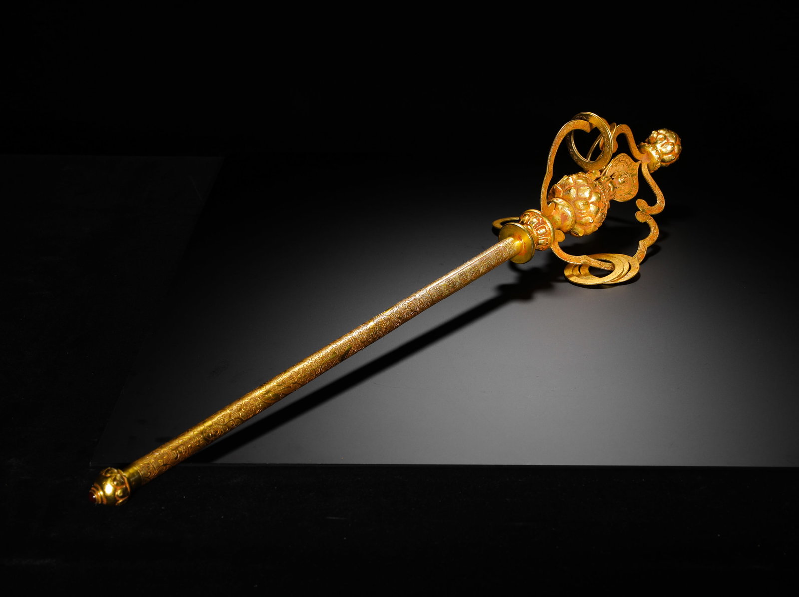 TANG DYNASTY GILDED BRONZE ZEN STAFF: H:68cmW:13cmWeight:1090g This is a gilt-bronze Buddhist staff of the Tang Dynasty. The entire body is gilded, with the shaft engraved with interlocking lotus patterns, and the head decorated with a lo