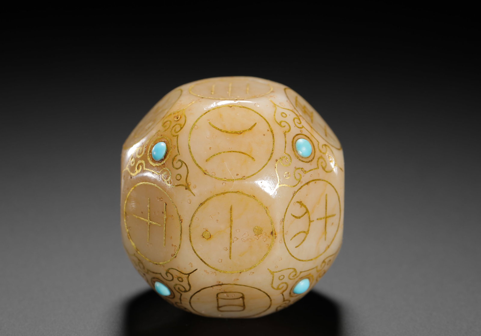 A TWELVE-SIDED DIVINATION DICE OF JADE INLAID WITH GOLD AND TURQUOISE FROM THE HAN DYNASTY: H:4.6cmW:4.6cmWeight:170g This dodecahedral jade die was used for ancient divination. Carved from nephrite, decorated with gold-inlaid trigram symbols and inlaid turquoise, it is a physical relic of a