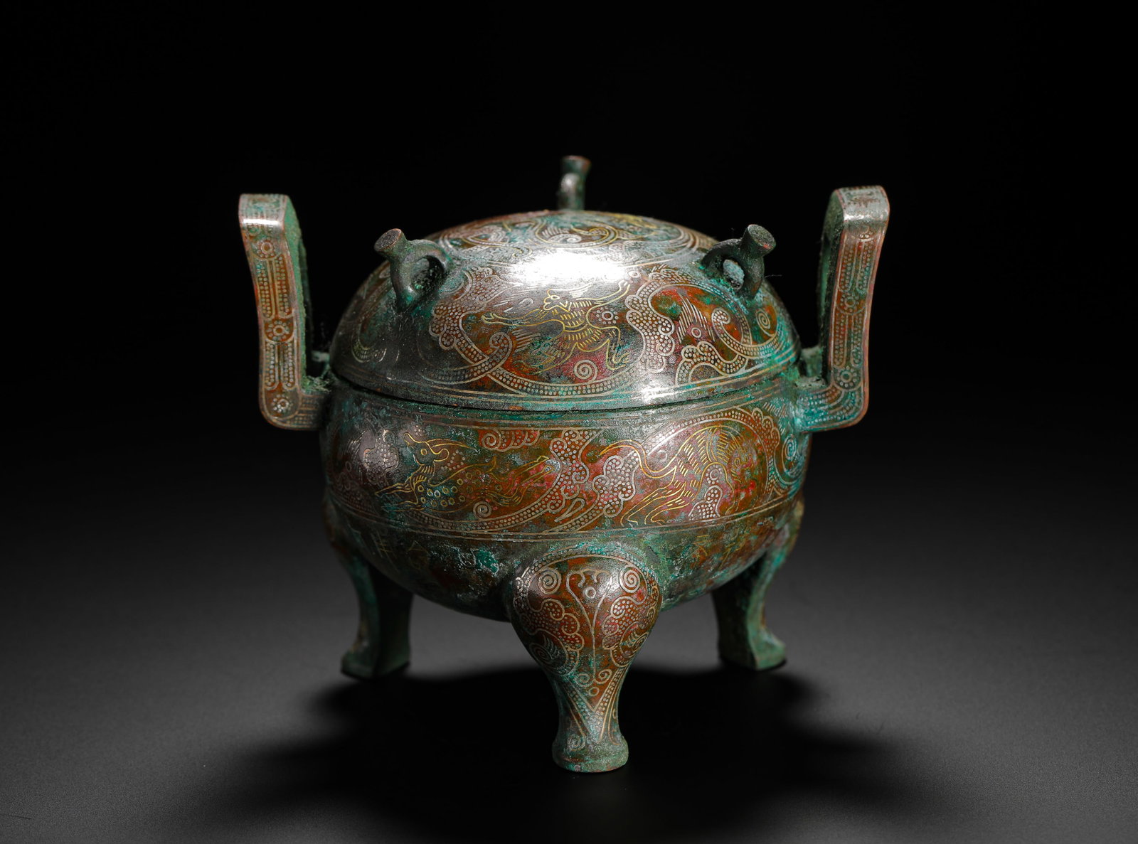 A TRIPOD WITH INLAID GOLD AND SILVER AUSPICIOUS BEAST PATTERNS FROM THE WARRING STATES PERIOD: H:7.5cmW:9cmWeight:380g This is a Warring States Period bronze ritual vessel. It is decorated with mythical beast patterns inlaid with gold and silver. With its dignified shape and exquisite craftsman