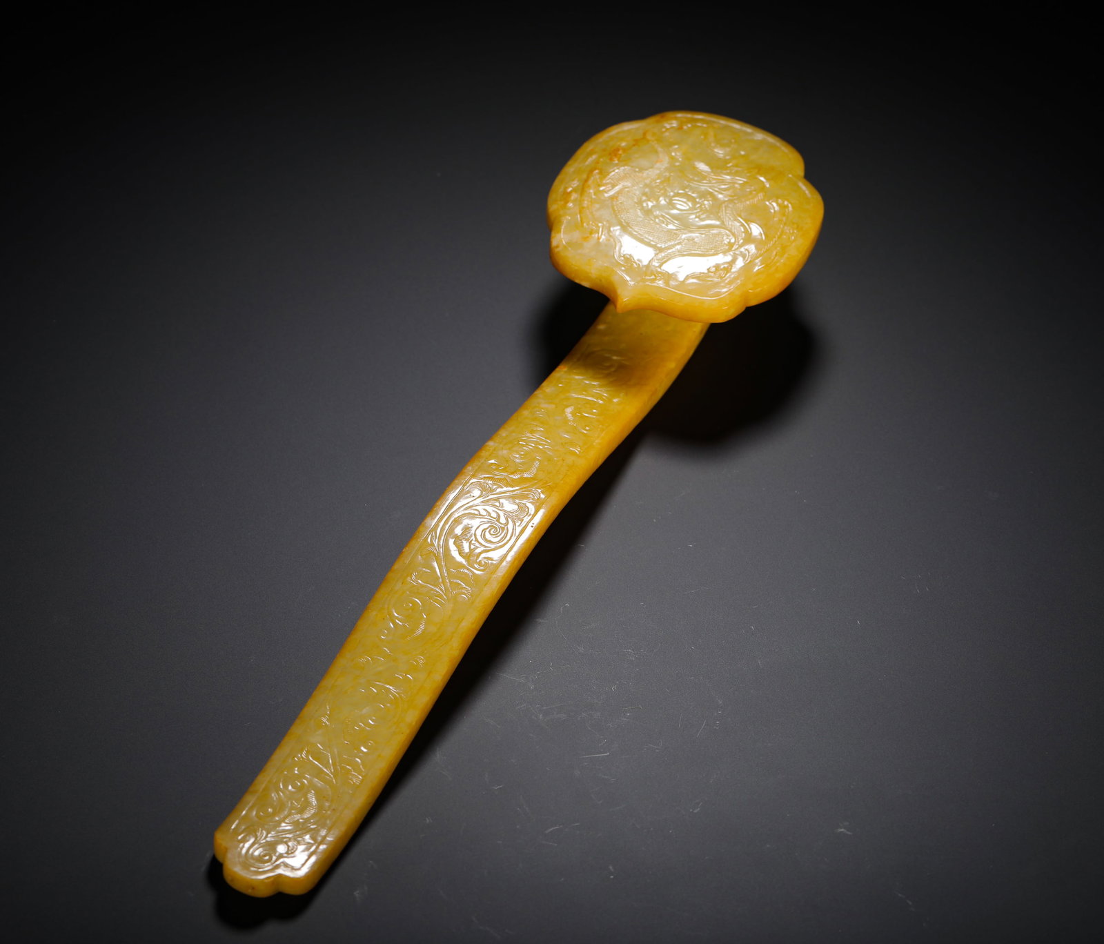 YELLOW JADE DRAGON PATTERN RUYI OF THE QING DYNASTY: H:32.5cm(12.80in)W:8.4cm(3.31in)Weight:370g(0.82lb)These objects were used as ritual utensils by Qing Dynasty nobles. The dragon and floral motifs symbolized good fortune and wealth, reflecting the