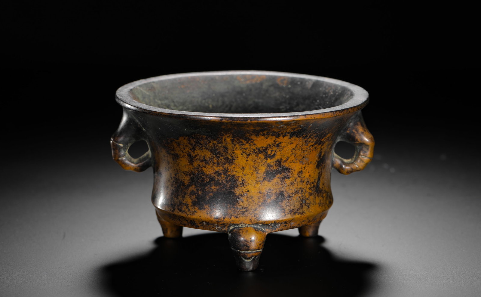 BRONZE ELEPHANT-EAR THREE-LEGGED FURNACE OF THE QING DYNASTY: H:7cmD:13cmWeight:1010g This is a Qing Dynasty bronze incense burner with a cylindrical body, elephant-head handles on both sides, and three legs. The base is inscribed with "Runliu Tang Zhi", exempli