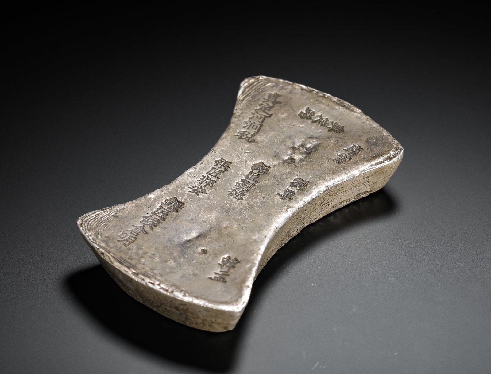 FIFTY TAELS OF SILVER INGOTS FOR THE ZHEN DING RIVER TAX OF THE JIN DYNASTY: H:2.5cm(0.98in) W:14.2cm(5.59in) Weight:1850g(4.08lb)This is a fifty-tael silver ting from the Jin dynasty, cast for the Hejian tax in Zhending Prefecture. It is a typical example of large official si