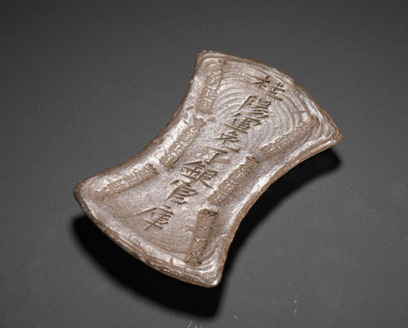 A TEN-TAEL SILVER INGOT FOR MILITARY TAX IN GUIYANG DURING THE SONG DYNASTY: H:1cm(0.39in) W:8.2cm(3.23in) Weight:350g(0.77lb)This is a fifty-tael silver ting from the Song dynasty, cast as tax silver for Guiyang Prefecture. It is a typical example of large official silver ing