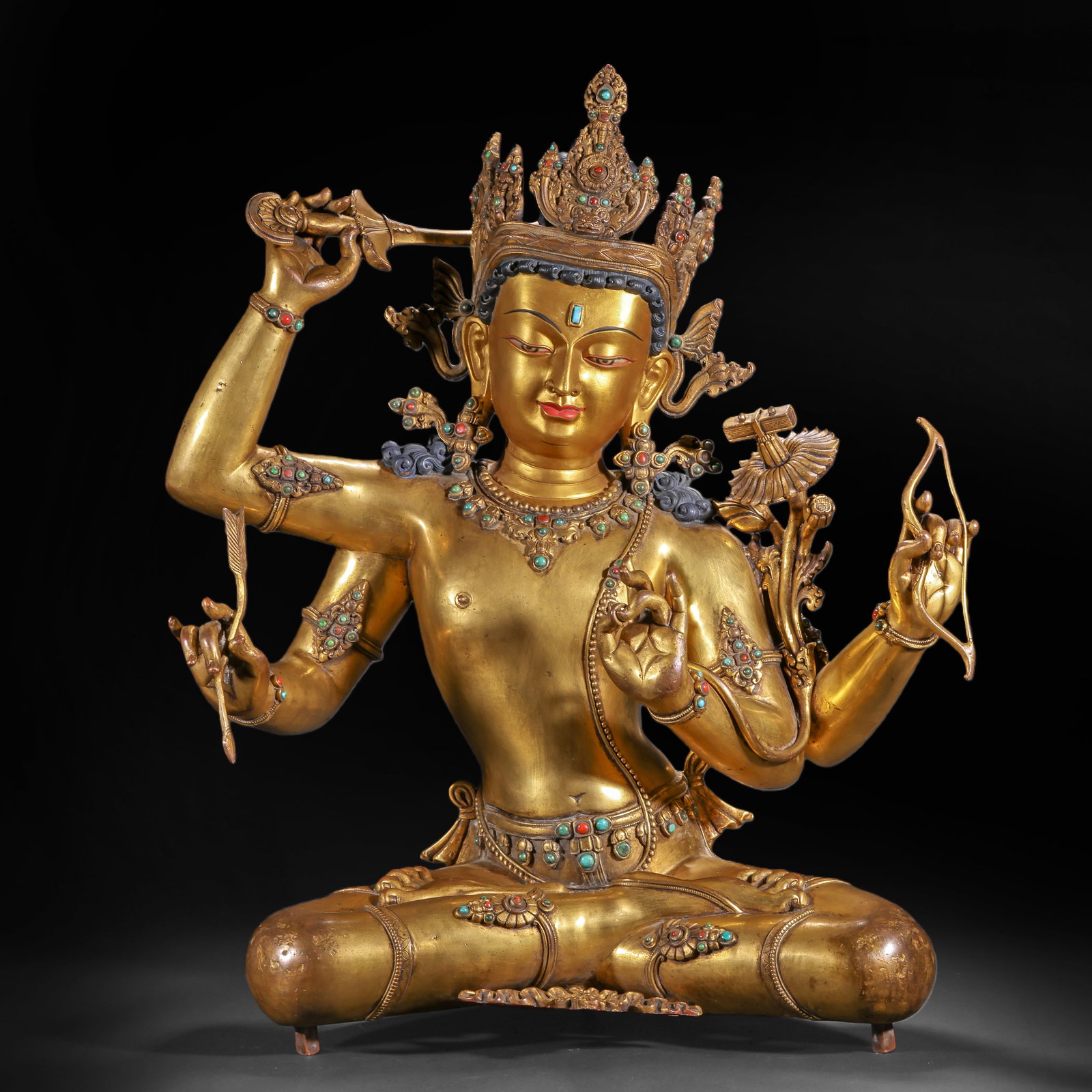 A SEATED STATUE OF MANJUSRI BODHISATTVA WITH GILDED BRONZE INLAYS FROM THE QING DYNASTY: H:55.0cm(21.65in) W:43.0cm(16.93in) Weight:14250g(31.42lb)This statue is cast in bronze and gilded. Six-Armed Manjushri Bodhisattva sits in a relaxed posture, wearing a five-leaf treasure crown with a