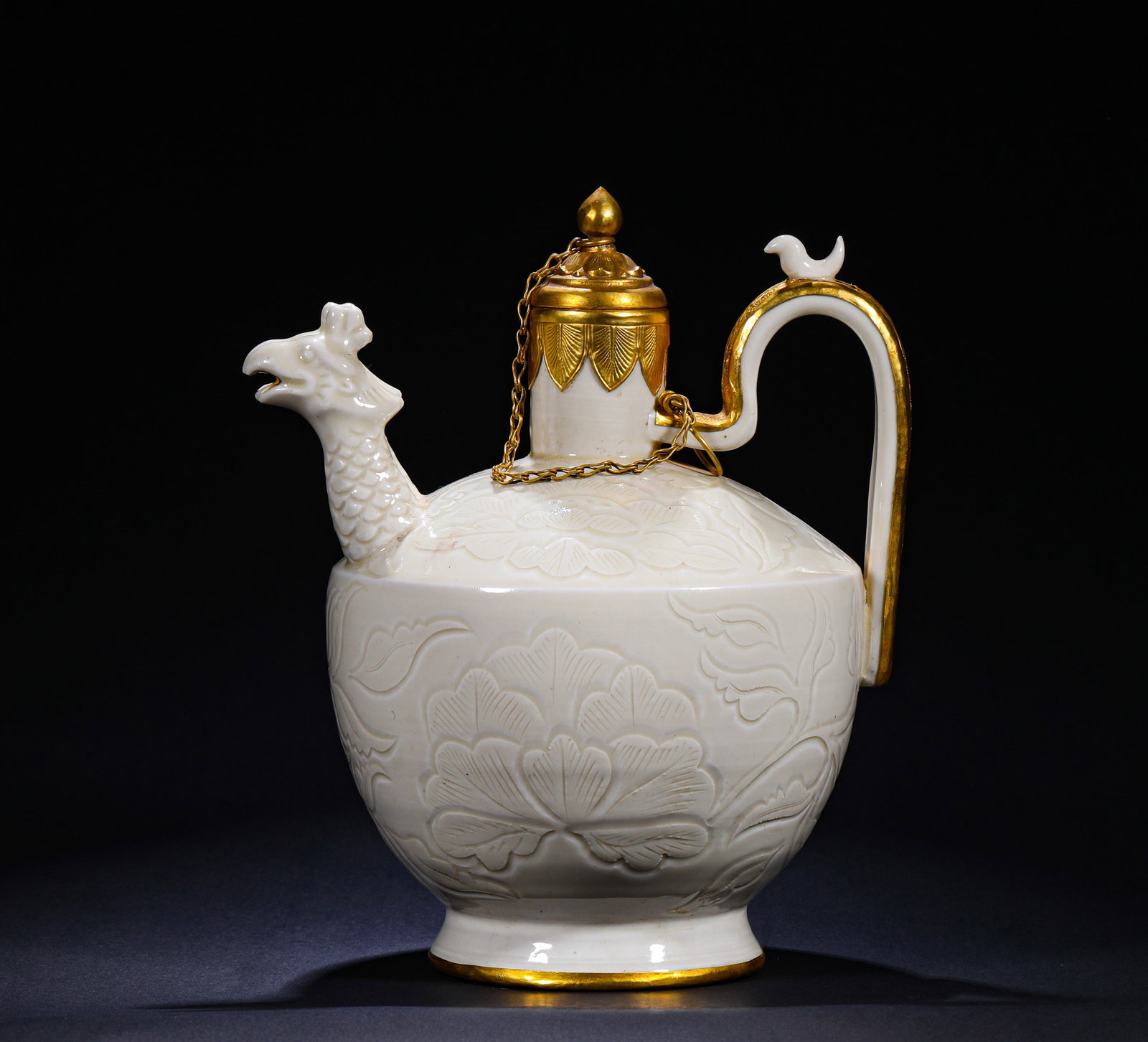 A WHITE GLAZED ENGRAVED FLOWER-SHAPED PHOENIX-HEAD TEAPOT FROM DING KILN OF THE NORTHERN SONG: H:22cm (8.66in) W:19cm (7.48in)This is a Northern Song Ding Kiln white-glazed carved phoenix-head ewer, crafted from Ding ware white porcelain with peony scroll patterns. Its phoenix-head spout comple