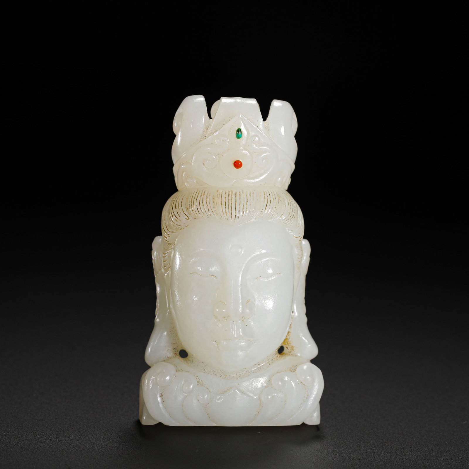 QING DYNASTY HETIAN WHITE JADE INLAID GUANYIN BUDDHA HEAD PENDANT: H:7.8CMW:3.7CMWEIGHT:140GQING DYNASTY HETIAN WHITE JADE GUANYIN HEAD PENDANT INLAID WITH RED AND GREEN GEMSTONES, WITH PERFORATED LOTUS BASE.