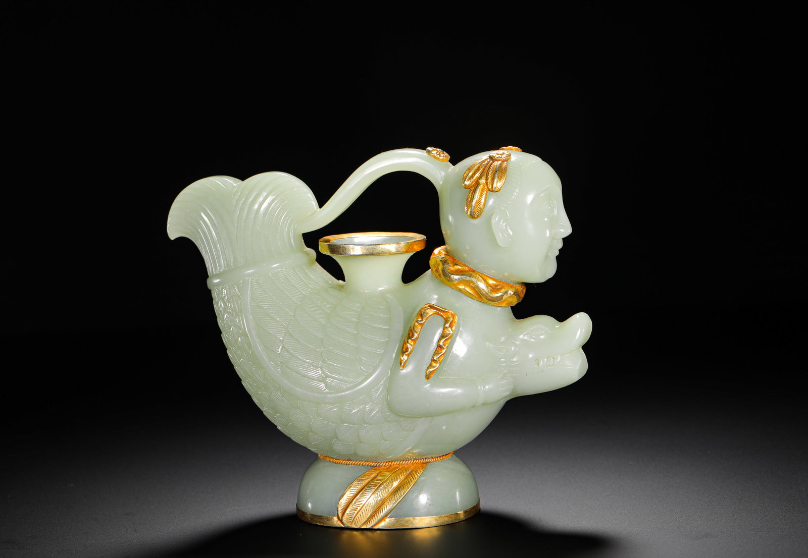 QING DYNASTY HETIAN GREEN AND WHITE JADE WRAPPED WITH GOLD MERMAID TRANSFORMED INTO DRAGON SHAPE: H:13.8CMW:15.5CMWEIGHT:730GQING DYNASTY CELADON HETIAN JADE GILT-INLAID EWER SHAPED AS HUMAN-FISH DRAGON CREATURE, FULLY CARVED WITH FISH SCALE PATTERNS AND ADORNED WITH SOLID GOLD ON HUMAN HEAD, NECK