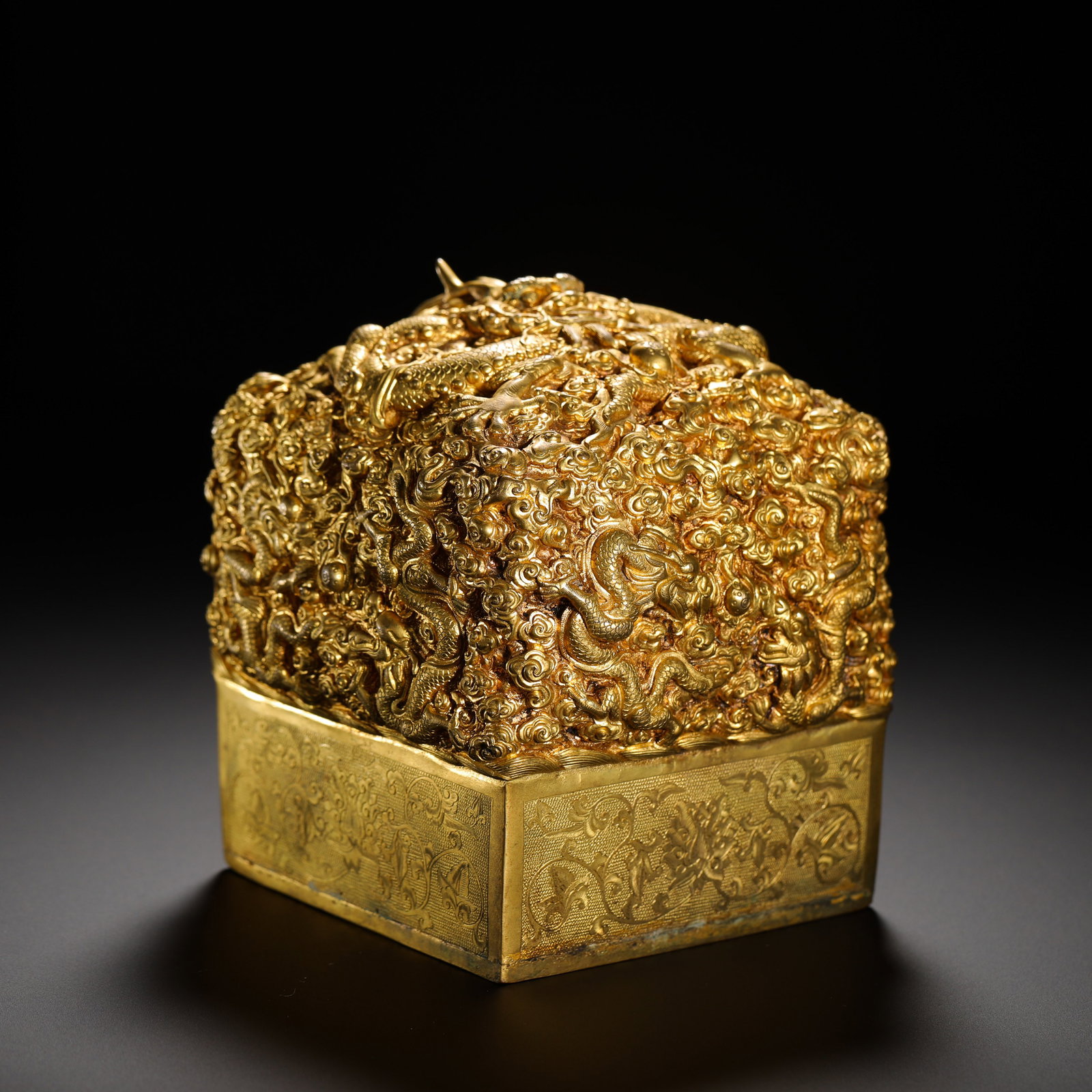GILDED BRONZE IMPERIAL SEAL WITH NINE DRAGONS AND AUSPICIOUS CLOUDS PATTERN: HEIGHT:12CM (4.72IN) WIDTH:11.5CM (4.53IN) WEIGHT:6980G (15.39LB) GILT BRONZE IMPERIAL SEAL CARVED WITH NINE DRAGONS AND AUSPICIOUS CLOUDS, QING DYNASTY. THE SQUARE BASE IS DECORATED WITH EIGHT TREASU
