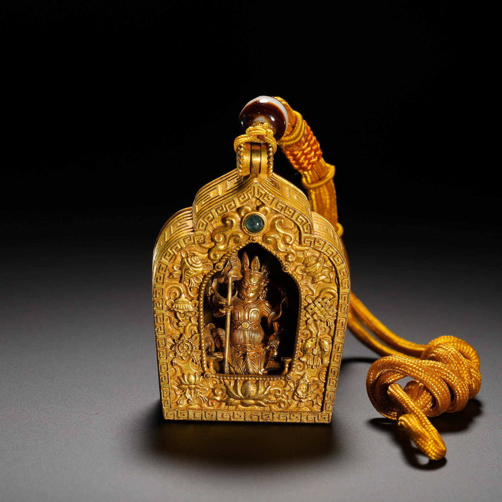 A GILT-BRONZE BOX OF THE EIGHT AUSPICIOUS GUARDIANS OF THE QING DYNASTY: HEIGHT:5.6CM (2.20IN) WIDTH:4.4CM (1.73IN) WEIGHT:85G (0.19LB) TIBETAN GILDED COPPER GAU SHRINE PENDANT IN NICHE ARCHED FORM. THE SURFACE IS FULLY CARVED WITH EIGHT AUSPICIOUS SYMBOLS AND INTERLOCKING