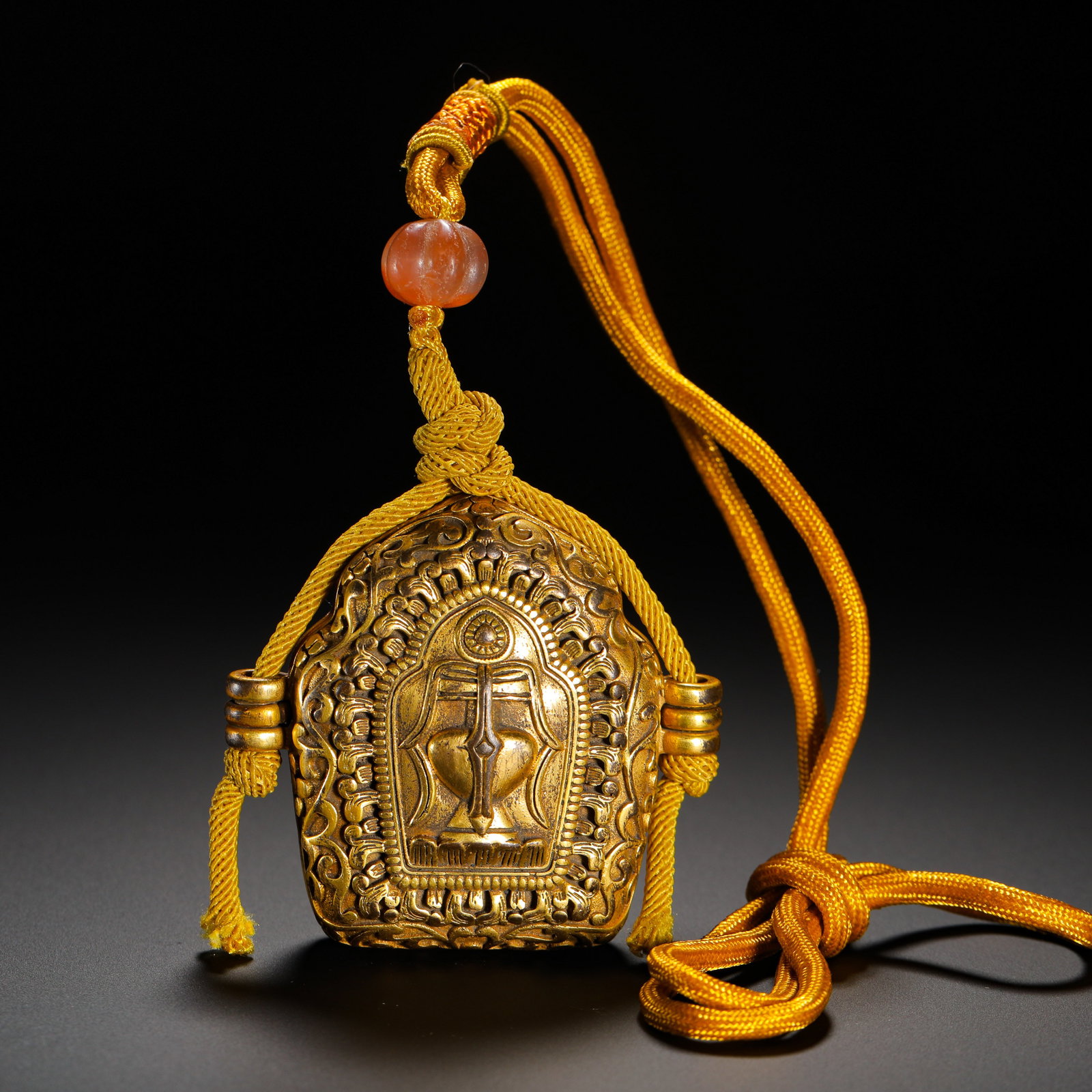 QING DYNASTY GILDED COPPER VASE PATTERN PORTABLE GAU BOX: HEIGHT:5.6CM (2.20IN) WIDTH:5.8CM (2.28IN) WEIGHT:86G (0.19LB) QING TIBETAN GILDED COPPER GAU PENDANT IN SHRINE SHAPE. THE SURFACE IS FULLY ENGRAVED WITH WINDING LOTUS SCROLLS, CENTERED ON EMBOSSED TR