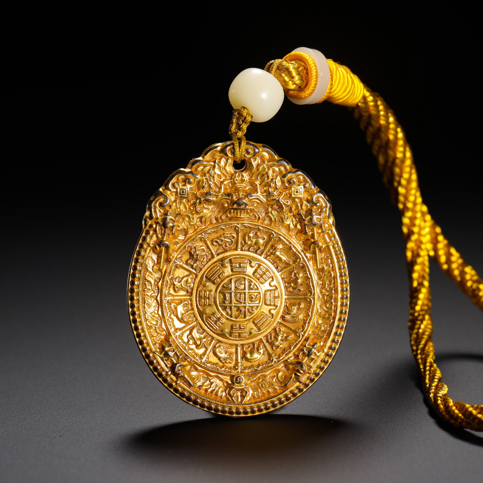 BRONZE GILDED NINE PALACES AND EIGHT TRIGRAMS AMULET OF THE QING DYNASTY: HEIGHT:5.3CM (2.09IN) WIDTH:4.3CM (1.69IN) WEIGHT:51G (0.11LB) QING TIBETAN GILDED COPPER NINE-PALACE ZODIAC AMULET IN RUYI CLOUD OUTLINE. THE TOP IS CARVED WITH TAOTIE BEAST HEAD, SURROUNDED BY EIGHT