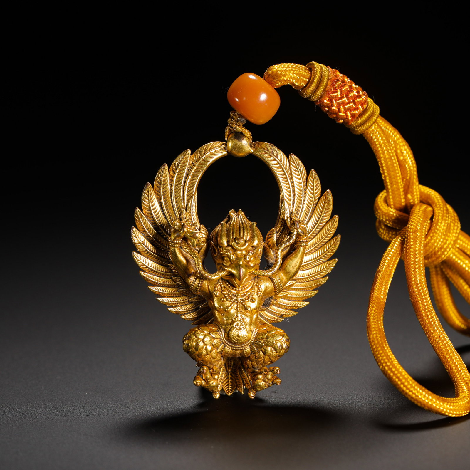 QING DYNASTY GILDED BRONZE PENDANT OF THE GREAT PENG BIRD: HEIGHT:5.7CM (2.24IN) WIDTH:4CM (1.57IN) WEIGHT:33G (0.07LB) QING TIBETAN HOLLOW GILDED COPPER GARUDA PENDANT. INTEGRALLY CAST WITH OPENWORK DESIGN, THE CENTRAL GARUDA FEATURES BEAST FACE, EAGLE BEAK,