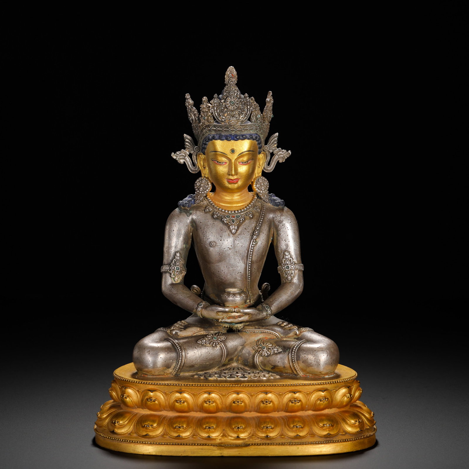 A QING DYNASTY GILDED SILVER STATUE OF THE BUDDHA OF INFINITE LIFE: HEIGHT:23CM (9.06IN) WIDTH:16CM (6.30IN) WEIGHT:1780G (3.92LB) SILVER BODY WITH GILDED COPPER BASE STATUE OF AMITAYUS, QING TIBETAN BUDDHISM. THE BODY IS FORGED PURE SILVER, FACE COATED WITH MUD GOLD,