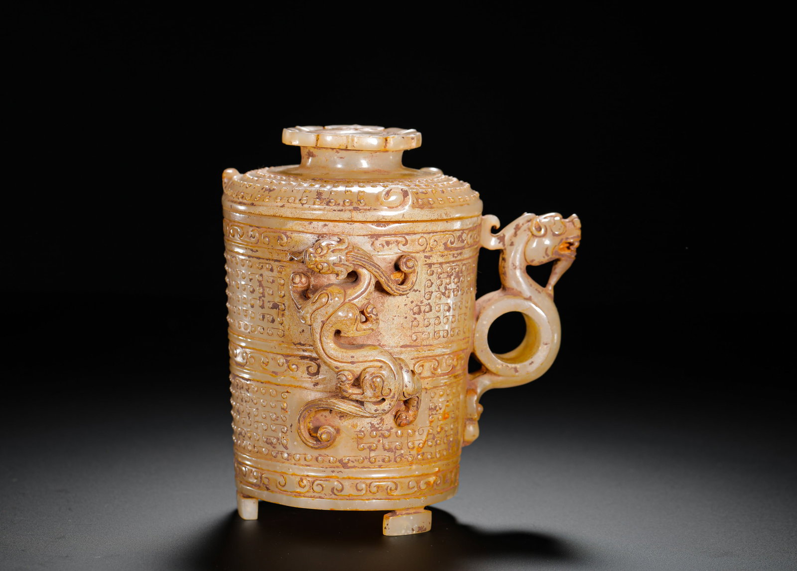 HAN DYNASTY ANCIENT JADE MANQIN GRAIN PATTERN CHILONG SINGLE-EARED THREE-LEGGED ? CUP: H:13CMW:12CMWEIGHT:500GHAN DYNASTY FULLY PATINATED ANCIENT JADE THREE-FOOT WINE ZHI CUP WITH GRAIN PATTERNS AND CHILONG DRAGON DECORATION, EMBOSSED CLIMBING DRAGON ON THE BARREL, HOLLOW DRAGON-HEAD RI