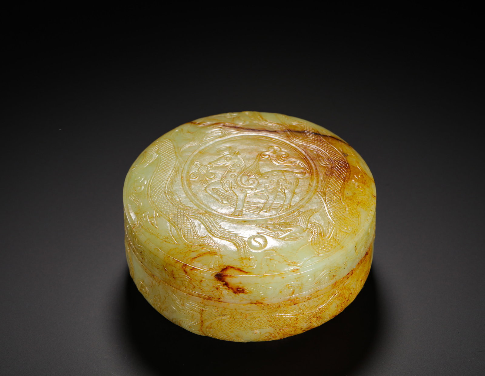 QING DYNASTY HETIAN HUANGQIN JADE ROUND DRAGON, PHOENIX AND CELESTIAL HORSE PATTERN SEAL PASTE BOX: H:6CMW:12.5CMWEIGHT:710GQING DYNASTY YELLOW-RUSSET HETIAN JADE CIRCULAR SEAL PASTE BOX CARVED WITH DRAGON, PHOENIX AND HEAVENLY STEED PATTERNS, THE LID CENTER FINELY INCISED WITH A FLOWER-BEARING WING