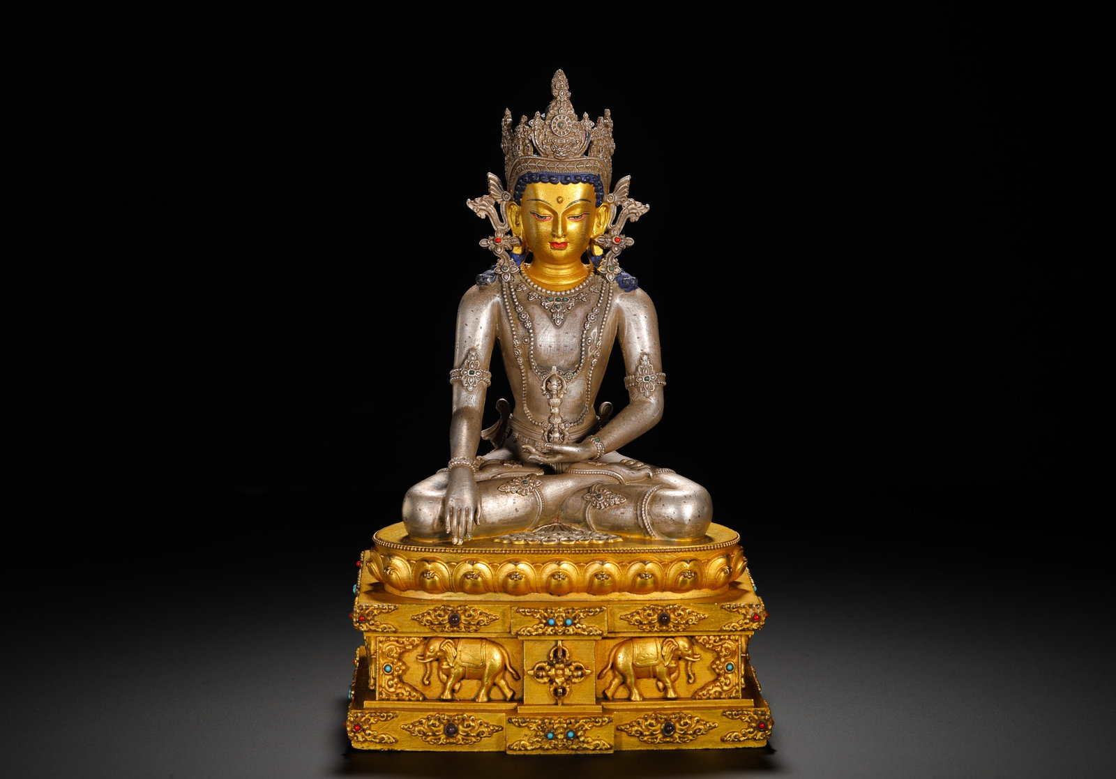 QING DYNASTY SILVER BODY GILDED BASE MOTIONLESS BUDDHA STATUE: HEIGHT:24CM (9.45IN) WIDTH:14CM (5.51IN) WEIGHT:2270G (5.00LB) COMPOSITE METAL STATUE OF AKSHOBHYA BUDDHA, QING TIBETAN BUDDHISM. THE BUDDHA??S BODY IS FORGED PURE SILVER WITH MUD-GILDED FACE, MULTI-L