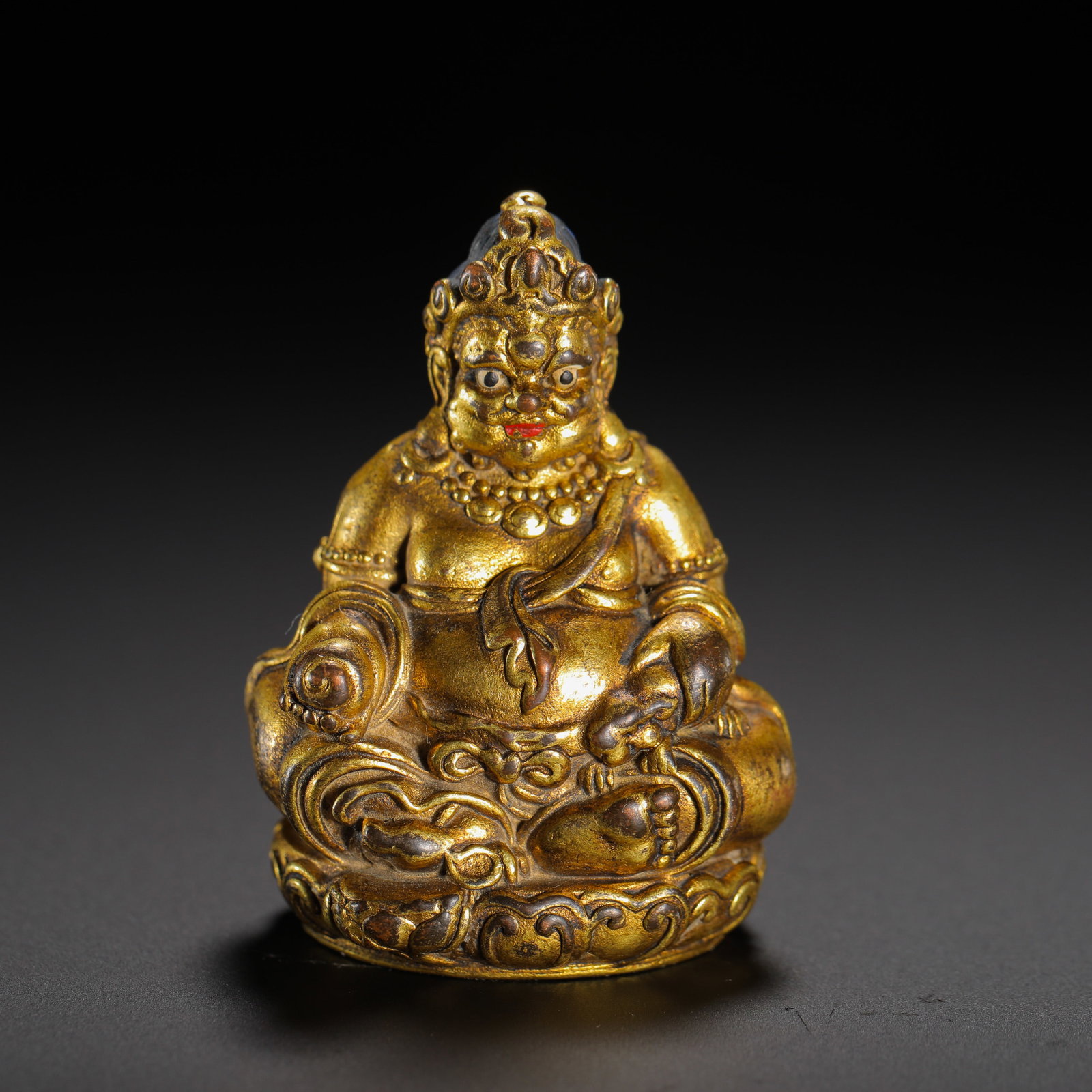 A GILDED BRONZE INCH-SIZED BUDDHA STATUE OF THE YELLOW GOD OF WEALTH IN THE QING DYNASTY: HEIGHT:5CM (1.97IN) WIDTH:3.7CM (1.46IN) WEIGHT:57G (0.13LB) MINI PORTABLE GILDED COPPER STATUE OF YELLOW JAMBHALA, QING TIBETAN BUDDHISM. SEATED IN RELAXED LALITASANA POSE ON LOTUS PEDESTAL, PLUMP TO