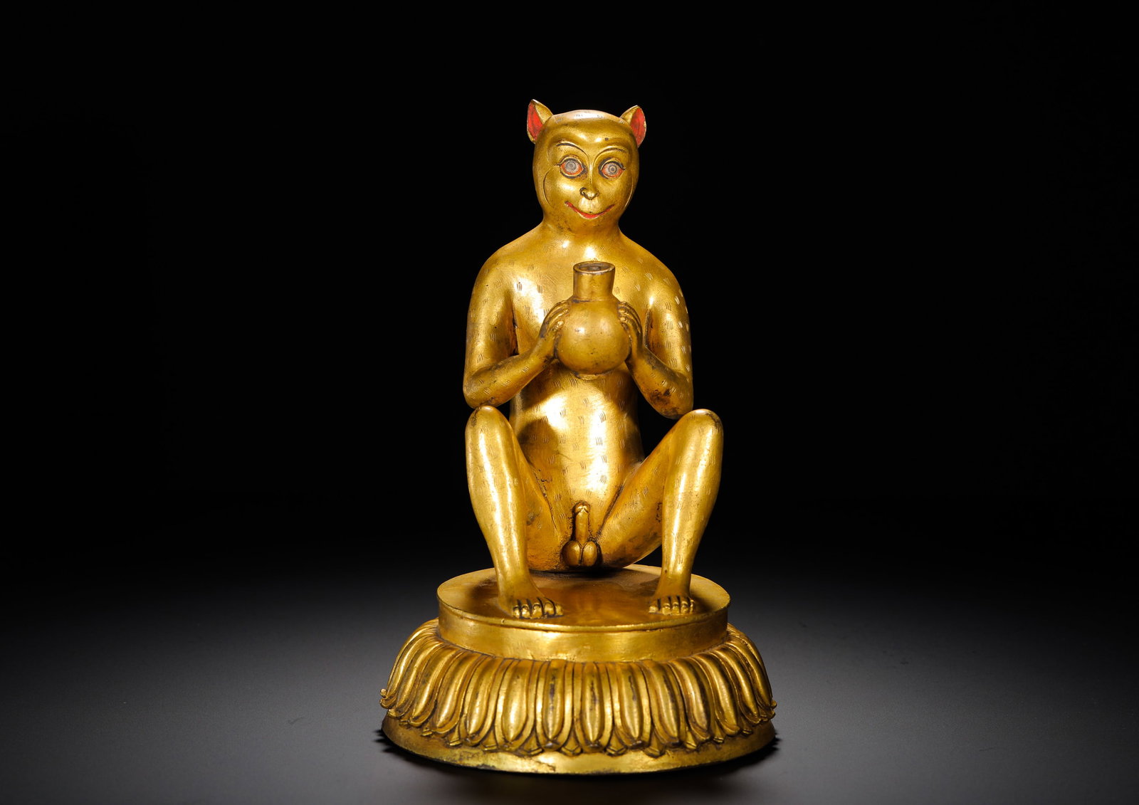 A GILDED BRONZE STATUE OF A MONKEY OFFERING VASE FROM THE QING DYNASTY: HEIGHT:21CM (8.27IN) WIDTH:13.5CM (5.31IN) WEIGHT:2050GGILDED COPPER STATUE OF OFFERING MONKEY, QING TIBETAN BUDDHISM. FULLY COVERED IN GILDING, THE MONKEY CROUCHES ON SINGLE-TIER LOTUS PEDESTAL WITH 