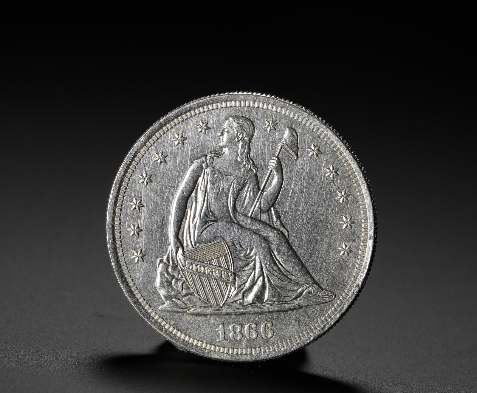 AMERICAN SILVER COIN: D:3.9CM (1.54IN) WEIGHT:27G (0.06LB) A KEY-DATE ISSUE OF THE SEATED LIBERTY SILVER DOLLAR SERIES, MINTED IN 1866 AS THE FIRST YEAR TO INCLUDE THE NATIONAL MOTTO "IN GOD WE TRUST" ON THE COIN, CARRYING